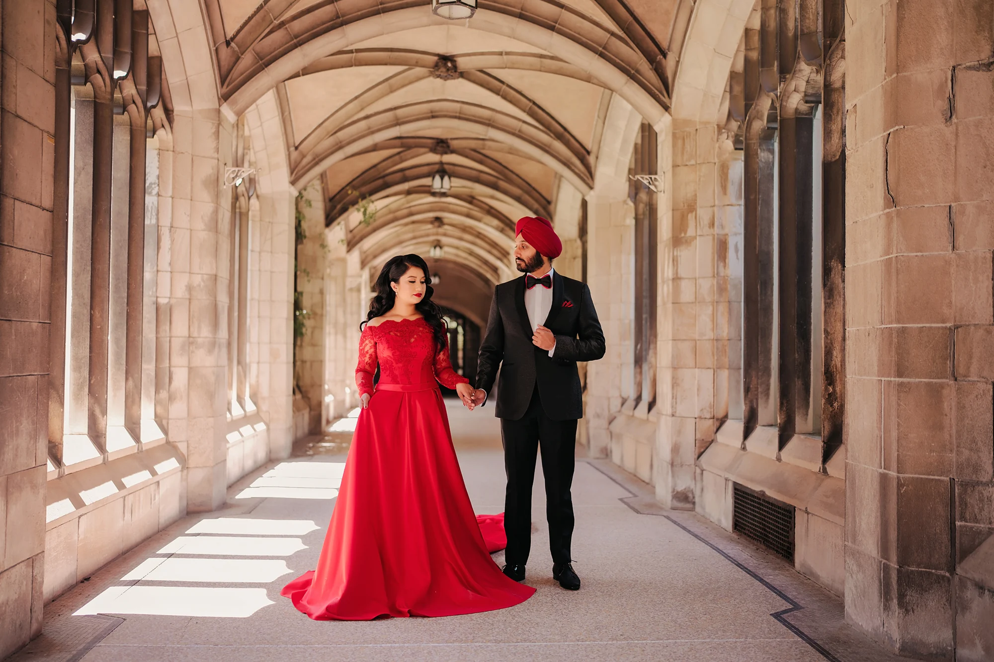 South Asian engagement photoshoot: red off-shoulder lace long-train gown in stone archway